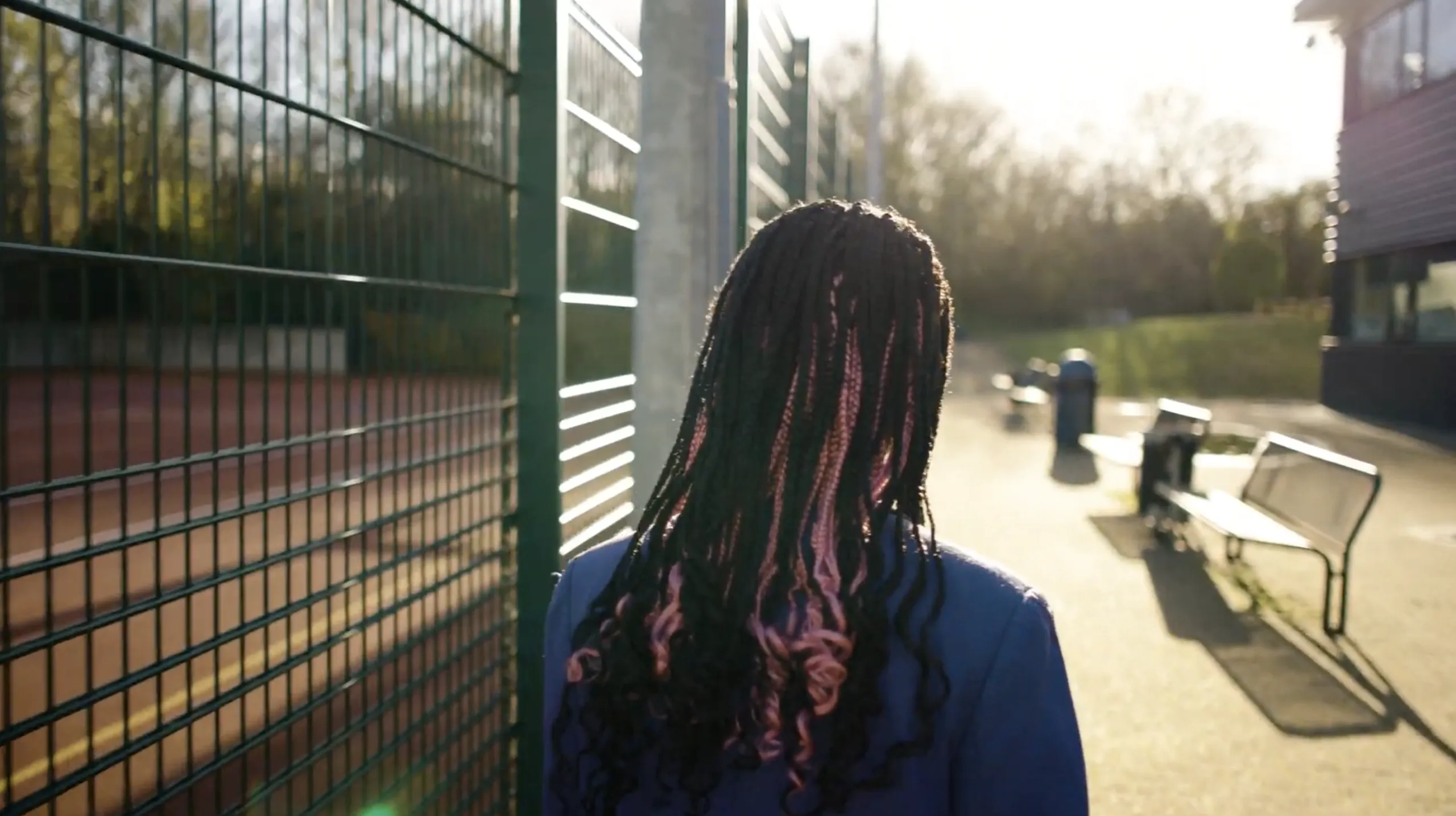 Young girl walking along a fence.